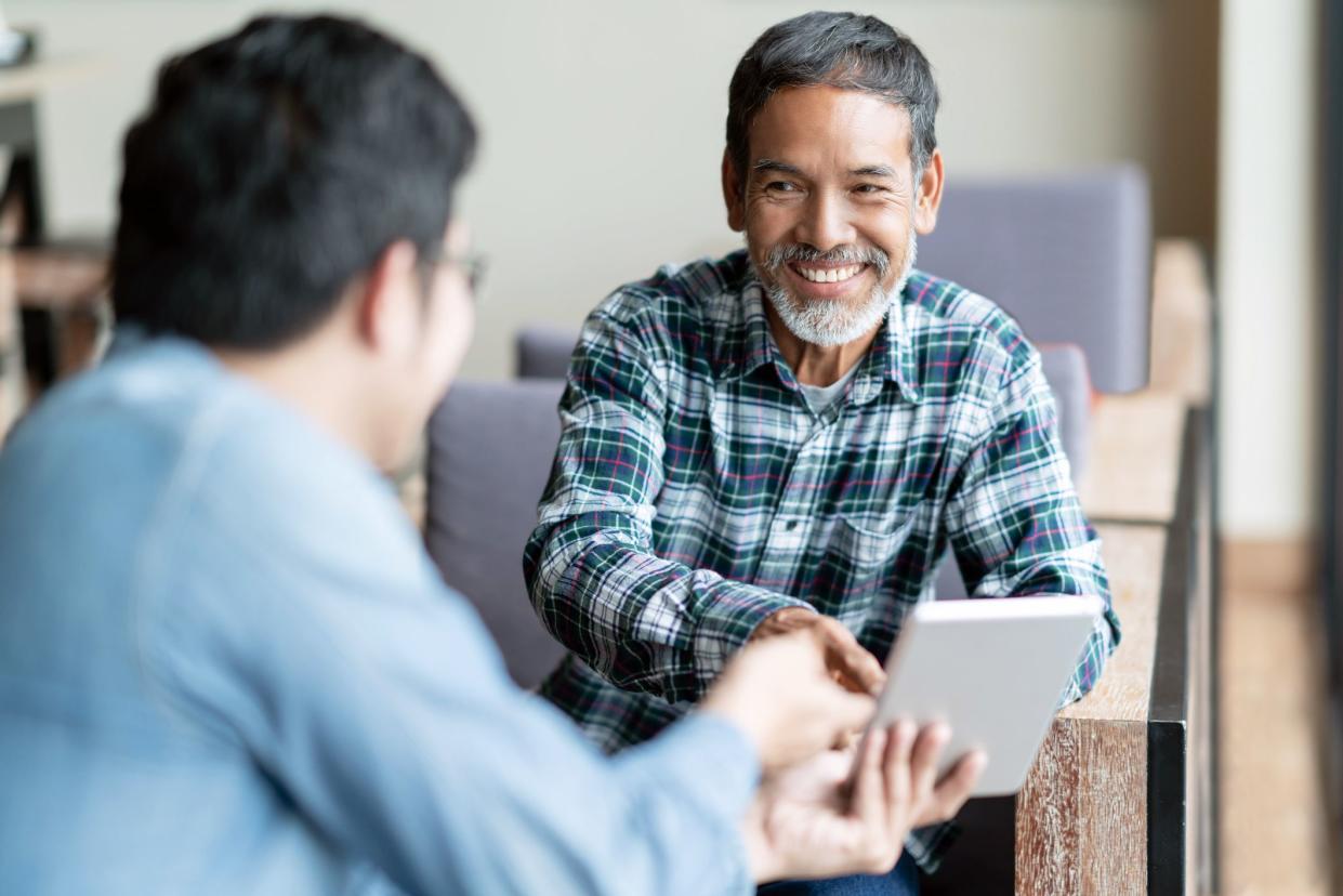 middle-aged man taking tablet from coworker