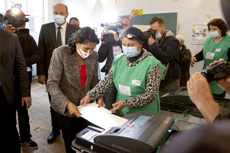 Georgia's President Salome Zurabishvili, center left, wearing a face mask to help curb the spread of the coronavirus, casts her ballot at a polling station during national municipal elections in Tbilisi, Georgia, Saturday, Oct. 2, 2021. Former President Mikheil Saakashvili was arrested after returning to Georgia, the government said Friday, a move that came as the ex-leader sought to mobilize supporters ahead of the national municipal elections seen as critical to the country's political makeup. The elections started Saturday. (AP Photo/Zurab Tsertsvadze)