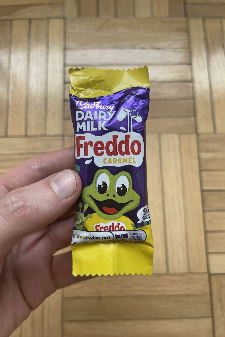 A hand holding a Cadbury Dairy Milk Freddo Caramel chocolate bar