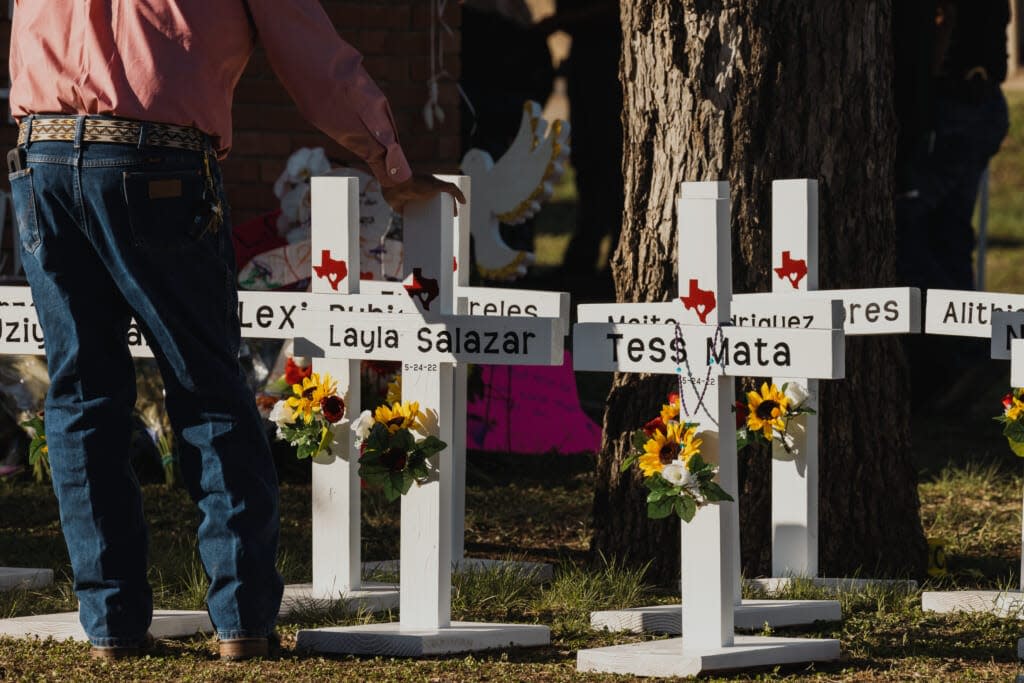 A man places his hand on a cross bearing the names of the victims of a mass shooting in front of Robb Elementary School on May 26, 2022 in Uvalde, Texas. (Photo by Jordan Vonderhaar/Getty Images)