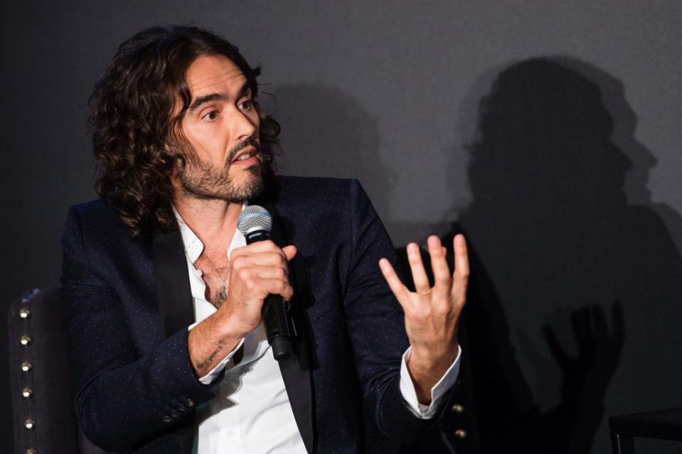 russell brand speaks on a microphone