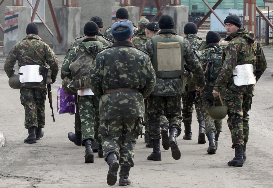 Soldiers walk near the armory of the Ukrainian army in the village of Poraskoveyevka, eastern Ukraine, Thursday, March 20, 2014. The disheveled men barricading the muddy lane leading into a military base in this eastern Ukraine village say they're taking a stand to defend Russian-speakers. (AP Photo/Sergei Grits)