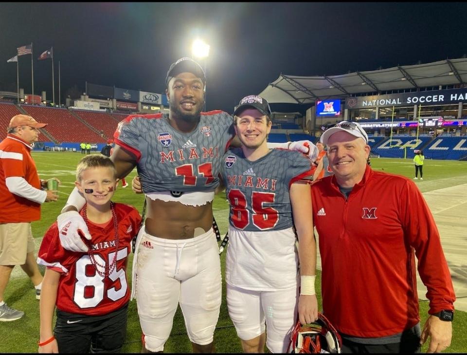 Dominique Robinson poses for a  photo with his former high school coach Dan Reardon (far right), and Reardon's two sons, Matthew (near right) and Patrick (far left), after Miami played in the Frisco Bowl, Dec. 23, 2021.