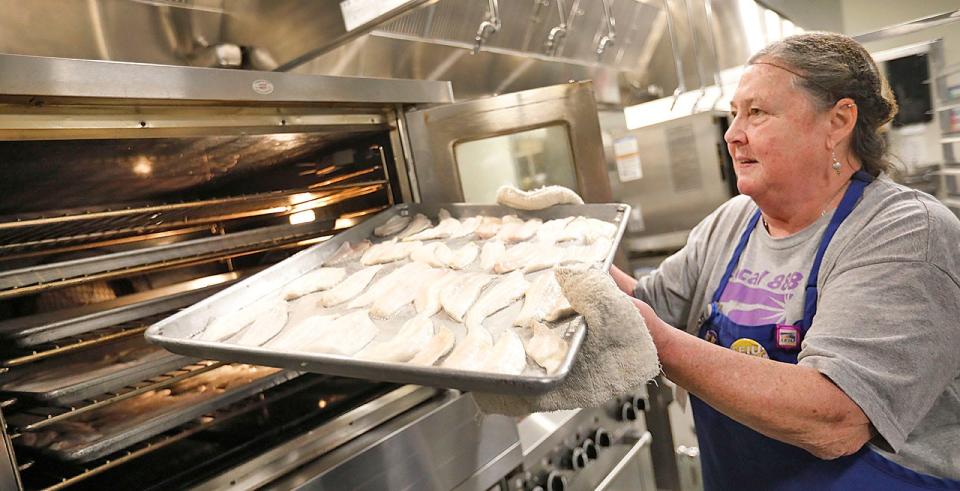 Cafeteria manager Louise "Mama Lou" Fitzgerald puts fresh fillets in the oven on Thursday, Jan. 12, 2023.