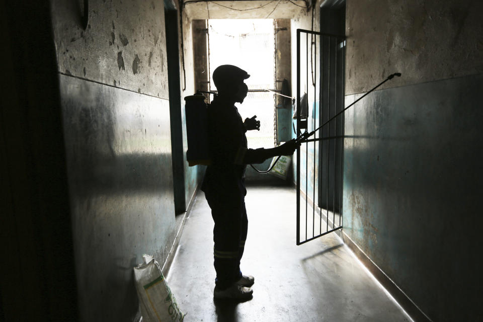 A man disinfects a wall to curb the spread of COVID-19 in Harare, Zimbabwe, Monday, Nov. 29, 2021. The World Health Organisation has urged countries not to impose flight bans on southern African countries due to concerns over the new omicron variant. (AP Photo/Tsvangirayi Mukwazhi)