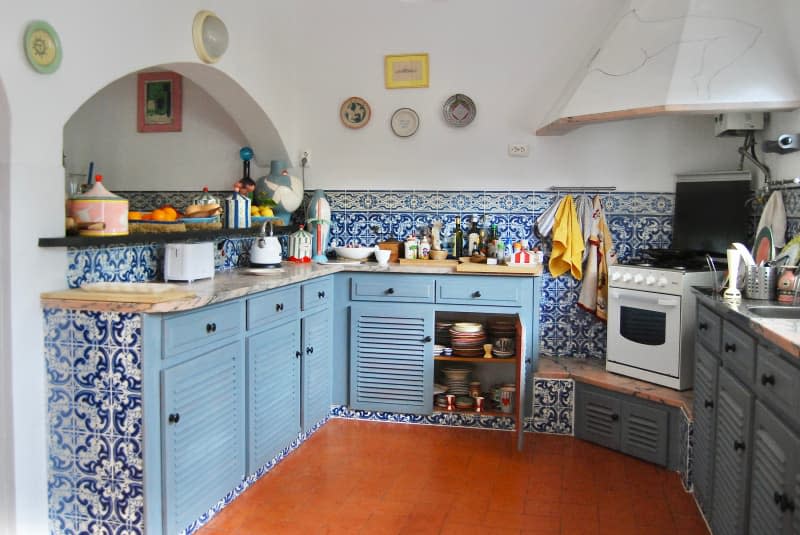 Kitchen with blue tiling and cabinets, and rust floor.