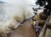 Chinese visitors watch as strong waves hit the coast of Xiamen, Fujian province, on September 21, 2013