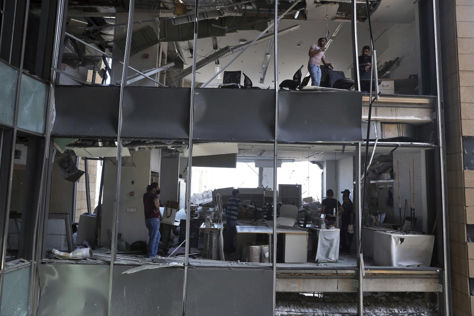 People stand inside a damaged building near the site of an explosion on Tuesday that hit the seaport of Beirut, Lebanon, Thursday, Aug. 6, 2020. The blast which appeared to have been caused by an accidental fire that ignited a stockpile of ammonium nitrate at the port, rippled across the Lebanese capital, killing at least 135 people, injuring more than 5,000 and causing widespread destruction. (AP Photo/Bilal Hussein)