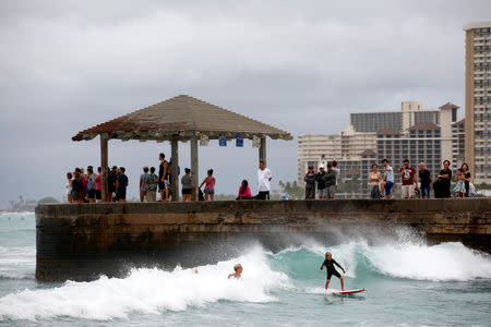 Tourists watch surfers in Waikiki Bay as Tropical Storm Lane approaches Honolulu, Hawaii, U.S. August 24, 2018. REUTERS/Terray Sylvester