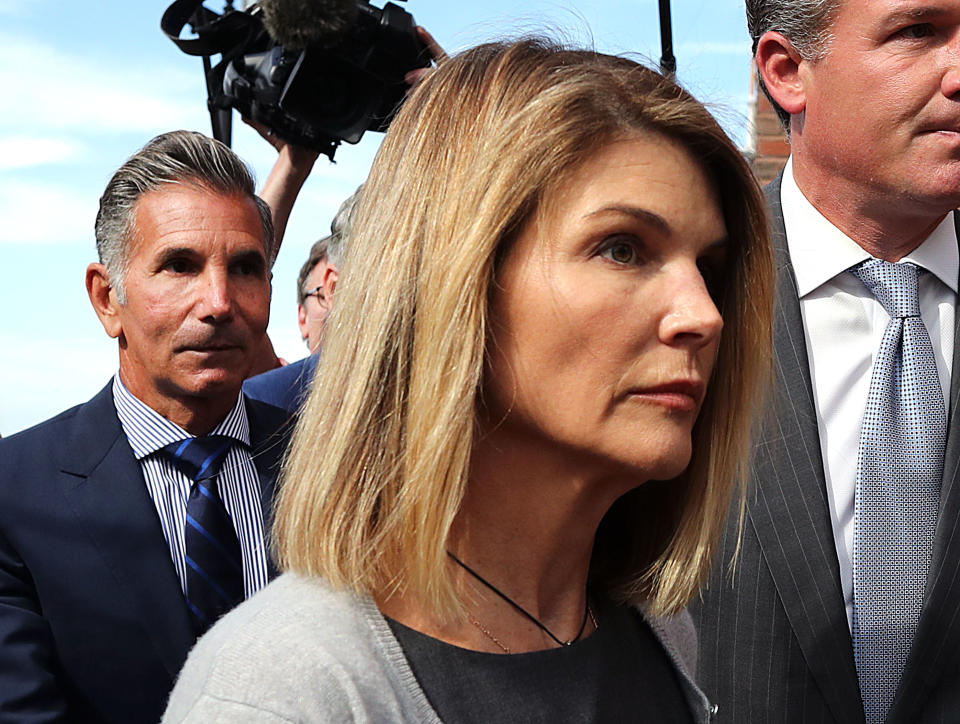 BOSTON, MA - AUGUST 27: Lori Loughlin and her husband Mossimo Giannulli, behind her at left, leave the John Joseph Moakley United States Courthouse in Boston on Aug. 27, 2019. A judge says actress Lori Loughlin and her fashion designer husband, Mossimo Giannulli, can continue using a law firm that recently represented the University of Southern California. The couple appeared in Boston federal court on Tuesday to settle a dispute over their choice of lawyers in a sweeping college admissions bribery case. Prosecutors had said their lawyers pose a potential conflict of interest. Loughlin and Giannulli say the firms work for USC was unrelated to the admissions case and was handled by different lawyers. (Photo by John Tlumacki/The Boston Globe via Getty Images)