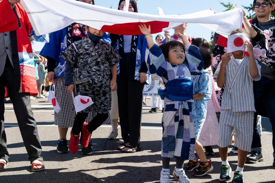 Children jump into and play with the Japanese flag while walking with the Japanese delegation as part of the Parade of Cultures during the International Food and Art Festival on Saturday, October 1, 2022, in Jackson, Tenn. 