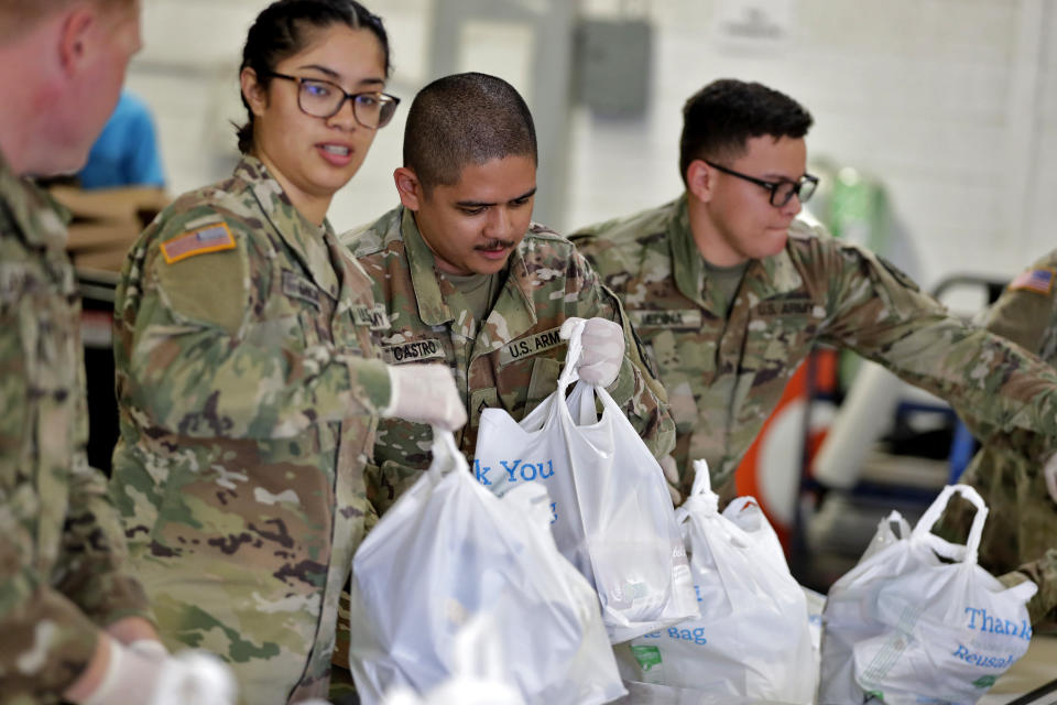 Members of the Arizona National Guard pack and sort food items at a food bank Thursday, March 26, 2020, in Mesa, Ariz. The Guard was at the food bank performing one of their first missions since they were activated by Gov. Doug Ducey to bolster the supply chain for food amid surging demand in response to the COVID-19 coronavirus outbreak. (AP Photo/Matt York)