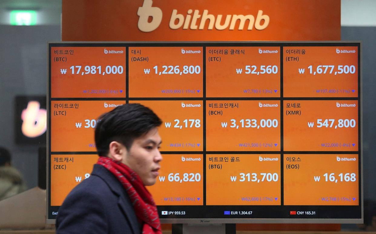 A man passes by a screen showing the prices of bitcoin at a virtual currency exchange office in Seoul, South Korea - Ahn Young-joon/AP