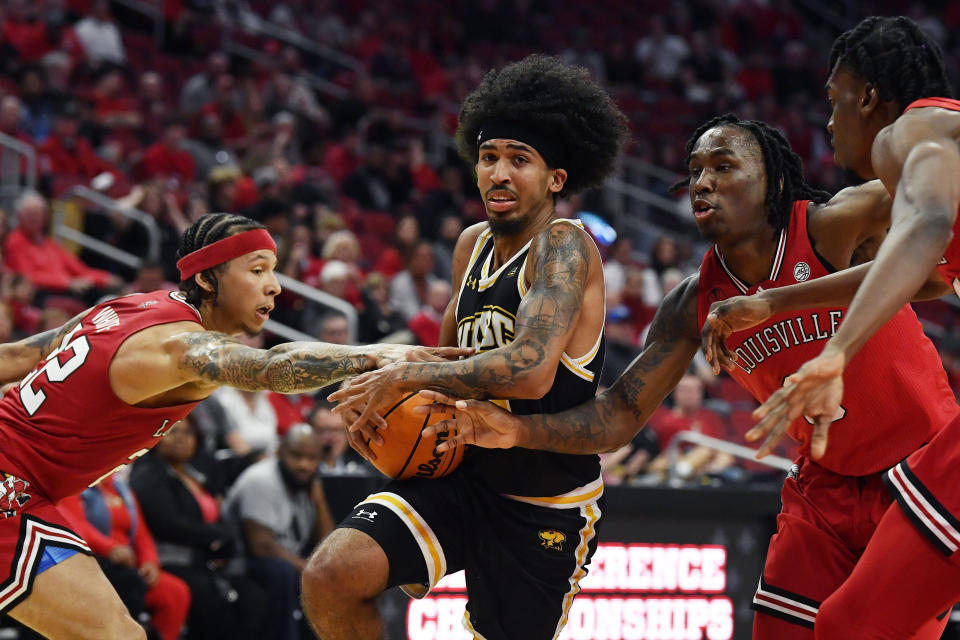 Maryland Baltimore County guard Bryce Johnson (23) fights his way through the defense of Louisville guard Tre White (22) and guard Mike James (0) during the first half of an NCAA college basketball game in Louisville, Ky., Monday, Nov. 6, 2023. (AP Photo/Timothy D. Easley)