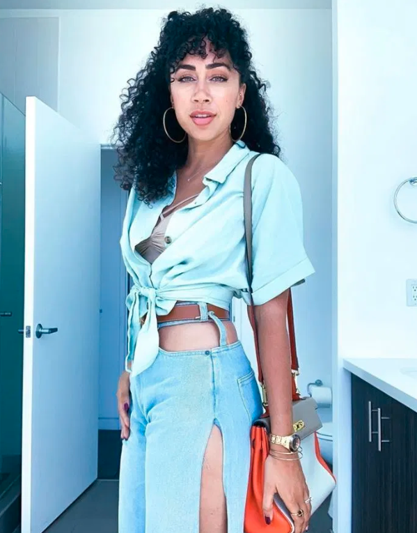 mixed-race woman poses in denim ensemble with curly hair tied back