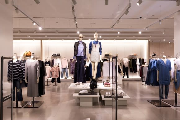 The interior of a women's clothing store floor filled with mannequins modeling trendy clothing.