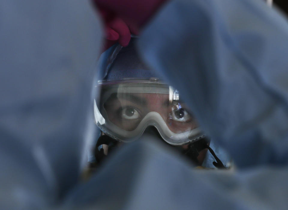 Paramedic Paulina Cervantes dresses to treat patients suspected to be infected with the new coronavirus in Iztapalapa, a Mexico City borough, Thursday, May 28, 2020. (AP Photo/Marco Ugarte)