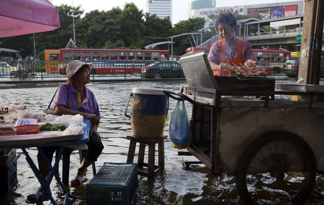 Tailandia ha vivido en 2011 las peores inundaciones que se recuerdan en los últimos cincuenta años. Durante meses, miles de pueblos, ciudades y aldeas se han visto afectadas por las lluvias y los torrentes incontenibles de agua. Aun así, la población ha intentado mantener sus rutinas diarias entre los ríos callejeros. Como estas mujeres que atendían sus puestos en Bangkok en mitad del agua el pasado 4 de noviembre. (Getty Images)