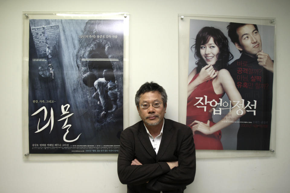 In this July 17, 2012 photo, Choi Yong-bae, Chungeoraham Film CEO and Producer, poses with posters produced by his company during an interview with the Associated Press at his office in Seoul, South Korea. After being turned down by many investors over the last four years, Choi said it feels strange and exciting that his revenge film about a notorious South Korean president blamed for the massacre of democracy protesters is finally coming to life through online donations. (AP Photo/Ahn Young-joon)