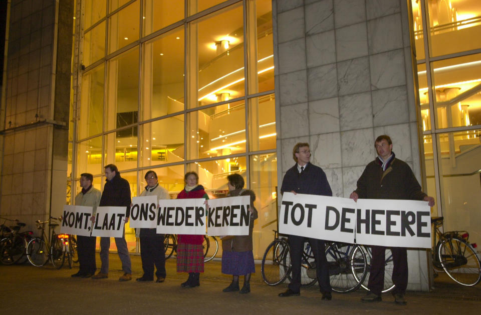 Demonstrators stand outside Amsterdam's City Hall holding a biblical text from the Old Testament reading "come let us return to the Lord" on April 1, 2001. Twenty years ago, the mayor of Amsterdam married four couples as the Netherlands became the first country in the world with legalized same-sex marriages. (AP Photo/Peter Dejong)