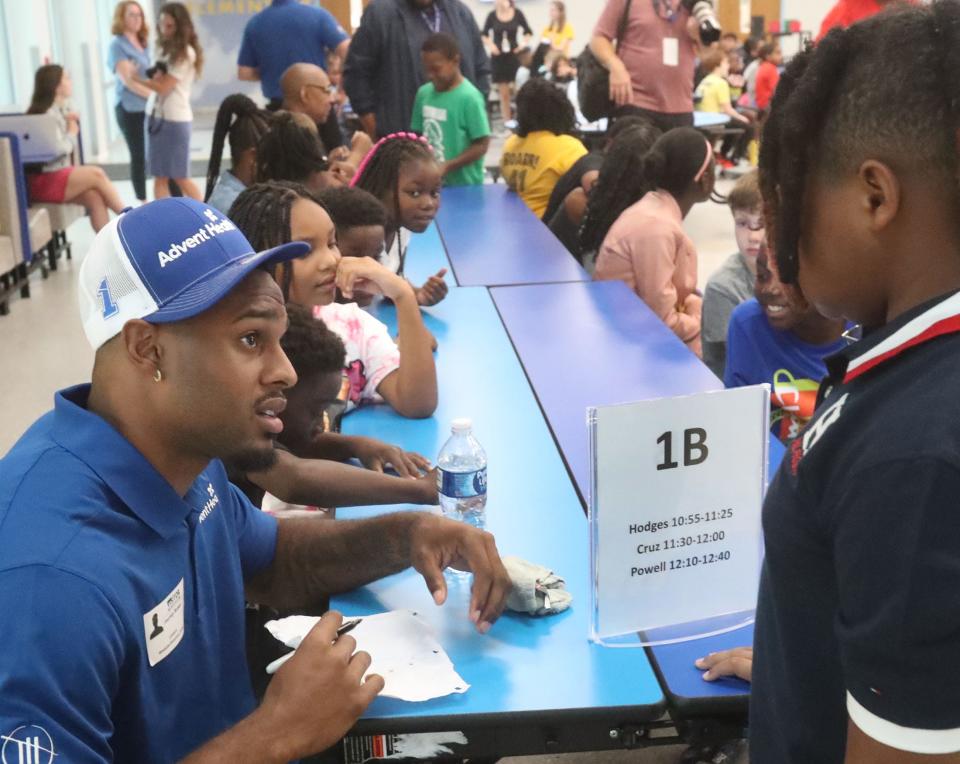 Former Penn State football player and current NASCAR pit crew member Journey Brown signs an autograph for a student at an event in Daytona Beach, Fla., last summer. Brown is shifting from a promising football career that was derailed by a heart condition.