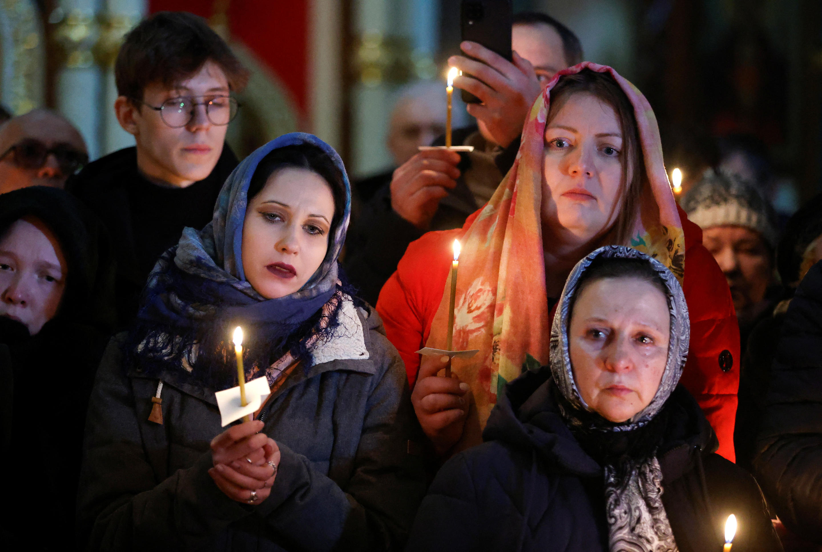 A dozen mourners hold candles inside the church at Navalny’s funeral service.