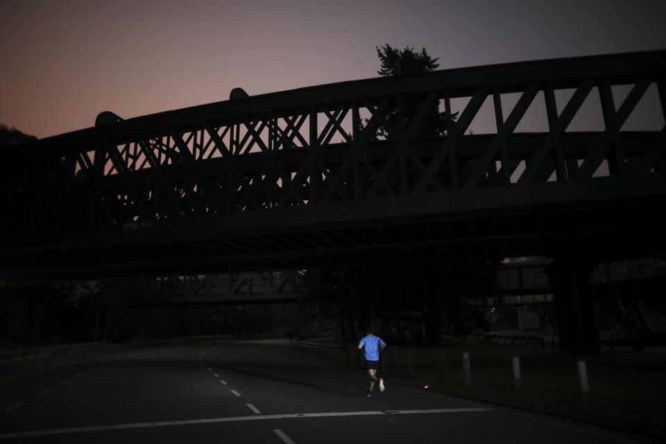 FILE - In this July 20, 2020 file photo, a man jogs during a government-ordered lockdown to curb the spread of the new coronavirus the first night after the city authorized outdoor exercise as part of rolling back restrictions in Buenos Aires, Argentina. People are on edge in Argentina, where the number of new coronavirus cases is surging despite nearly five months of strict limits on movement and activities in Buenos Aires and the surrounding area. (AP Photo/Natacha Pisarenko, File)