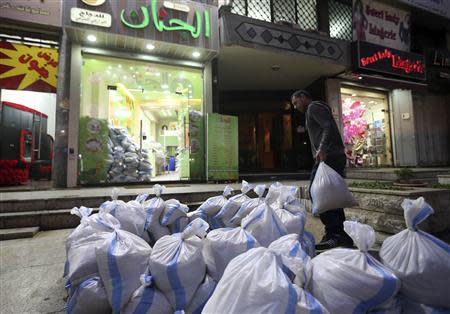 A man moves sandbags towards a shop as protection from future explosions at a stronghold of the Shi'ite group Hezbollah in the southern suburbs of the Lebanese capital Beirut January 28, 2014. REUTERS/Hasan Shaaban