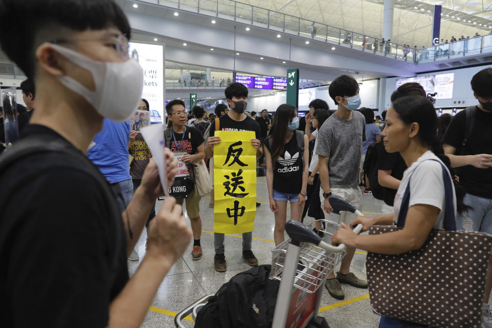 A protester holds up a banner that reads anti-extradition to China as thousands take part in a second day of sit-in protest at the airport in Hong Kong on Saturday, Aug. 10, 2019. Hong Kong is in its ninth week of demonstrations that began in response to a proposed extradition law but have expanded to include other grievances and demands for more democratic freedoms. (AP Photo/Kin Cheung)