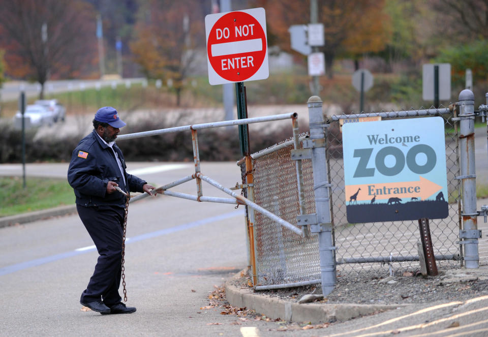 A security guard closes the gate at the Pittsburgh Zoo, where zoo officials say a young boy was killed after he fell into the exhibit that was home to a pack of African painted dogs, who pounced on the boy and mauled him, Sunday, Nov. 4, 2012. It’s not clear whether he died from the fall or the attack, said Barbara Baker, president and CEO of the Pittsburgh Zoo & PPG Aquarium. (AP Photo/John Heller)