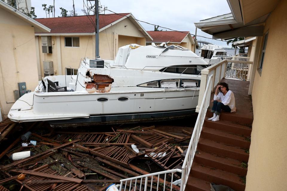 A damaged boat is wedged between low apartment buildings.