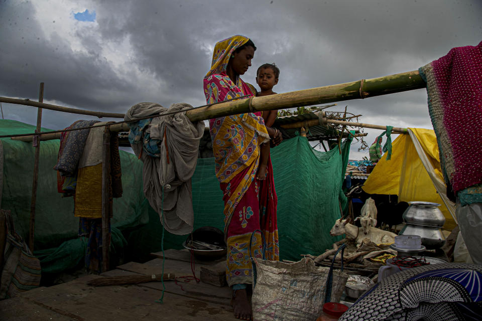 A flood affected woman and child take shelter at temporary structure near their submerged house along river Brahmaputra in Morigaon district, Assam, India, Thursday, July 16, 2020. Floods and landslides triggered by heavy monsoon rains have killed dozens of people in this northeastern region. (AP Photo/Anupam Nath)