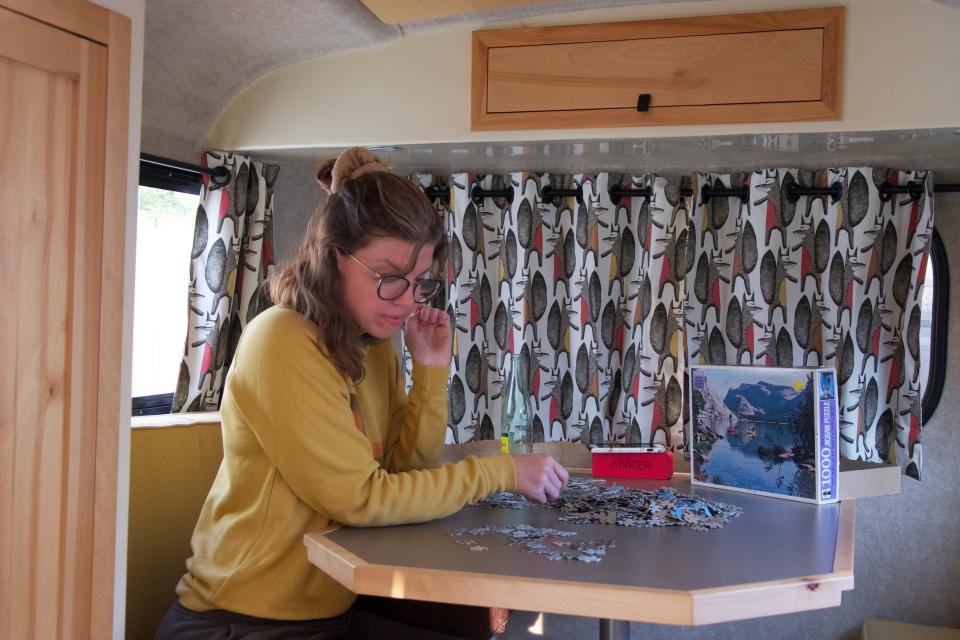 A woman sits at a desk in a travel trailer.
