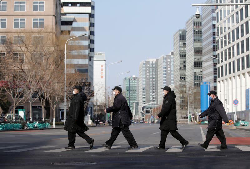 Security personnel wearing masks cross a road at the Financial Street in central Beijing