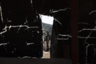 An Israeli soldier, seen through a hole in a tent, secures the area where Israel's military said troops killed a Palestinian man suspected of trying to attack soldiers, at a West Bank junction near the joint Israeli-Palestinian industrial zone of Barkan, Tuesday, Jan. 26, 2021. (AP Photo/Ariel