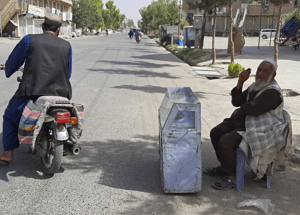 A man sells mobile recharge cards, one of the few vendors venturing out due to fighting nearby between the Taliban and Afghan security forces, in the city of Lashkar Gah, Helmand province, southern Afghanistan, Tuesday, Aug. 3, 2021. The Taliban pressed on with their advances in Afghanistan's southern Helmand province on Tuesday as Afghan forces launched airstrikes to defend the provincial capital. (AP Photo/Abdul Khaliq)