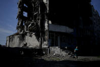 A woman walks past a building destroyed in Russian shelling in Borodyanka, on the outskirts of Kyiv, Ukraine, Tuesday, June 21, 2022. (AP Photo/Natacha Pisarenko)