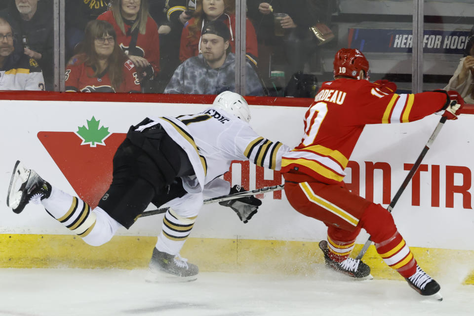 Boston Bruins' Trent Frederic, left, works against Calgary Flames' Jonathan Huberdeau during the first period of an NHL hockey game Thursday, Feb. 22, 2024, in Calgary, Alberta. (Larry MacDougal/The Canadian Press via AP)