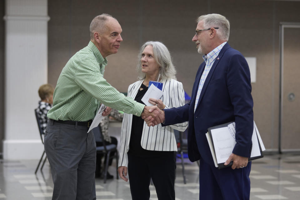 Paddy McGuire, Democrat incumbent Mason County auditor, left, shakes hands with his election opponent Republican Steve Duenkel, right, before a candidate forum, Thursday, Oct. 13, 2022, in Shelton, Wash. Between is Mason County Comissioner Sharon Trask. (AP Photo/John Froschauer)