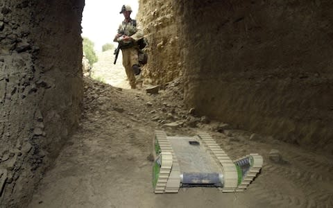 A U.S. Army soldier maneuvers Hermes the robot into a cave to detect mines, traps, and other unexploded ordnance  - Credit: AP