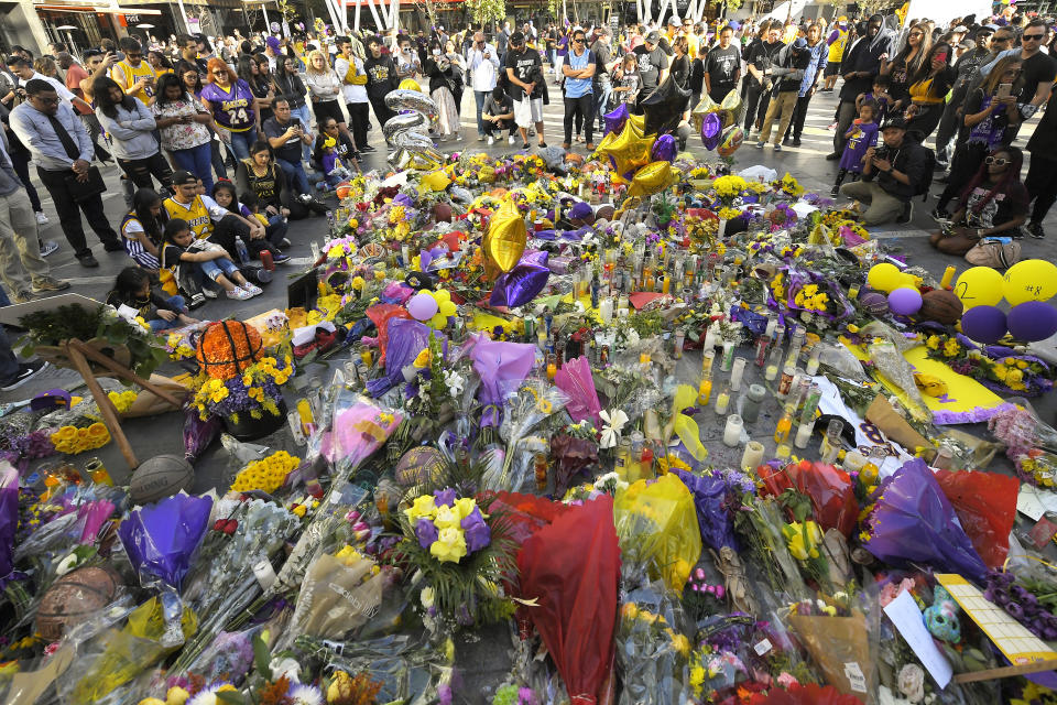 FILE - In this Jan. 28, 2020, fans gather in front of several memorials set up at LA Live, near Staples Center where the Los Angeles Lakers play, to memorialize Kobe Bryant in Los Angeles following a helicopter crash that killed the former NBA basketball player, his 13-year-old daughter, Gianna, and seven others. (AP Photo/Mark J. Terrill, File)