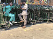 Vendors who make a living from pushing customer trollies wait for customers outside a supermarket in Harare, in this Wednesday, Oct, 9, 2019 photo. Hyperinflation is changing prices so quickly in the southern African nation that what you would see displayed on a supermarket shelf might change by the time you reach the checkout. (AP Photo/Tsvangirayi Mukwazhi)