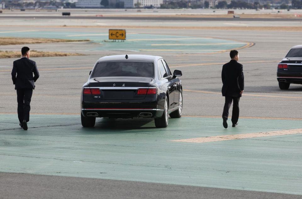 Security guards run next to China President Xi Jinping's car as he departs San Francisco International Airport.