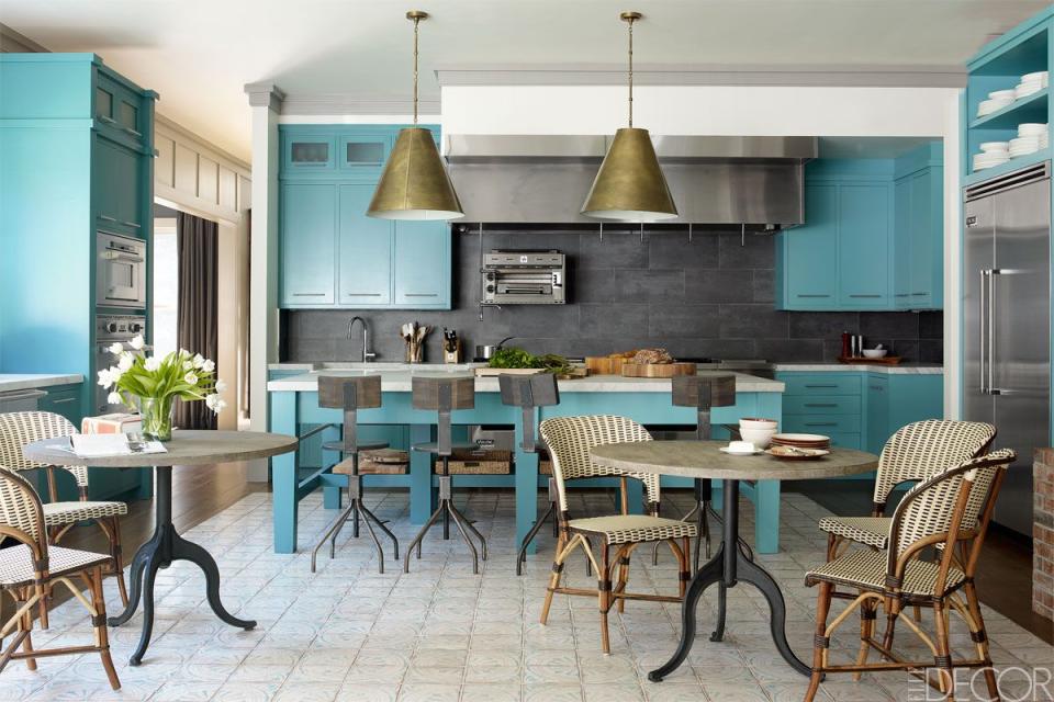 <p>The kitchen of this Hamptons home features custom-made cabinets and an island painted in <a rel="nofollow noopener" href="http://www.benjaminmoore.com/en-us/paint-color/majesticblue" target="_blank" data-ylk="slk:Benjamin Moore's Majestic Blue;elm:context_link;itc:0;sec:content-canvas" class="link ">Benjamin Moore's Majestic Blue</a>. The French bistro chairs are by <a rel="nofollow noopener" href="http://www.beaufurn.com" target="_blank" data-ylk="slk:Beaufurn;elm:context_link;itc:0;sec:content-canvas" class="link ">Beaufurn</a> and the brass pendants are by Thomas O'Brien for <a rel="nofollow noopener" href="http://www.visualcomfortlightinglights.com" target="_blank" data-ylk="slk:Visual Comfort;elm:context_link;itc:0;sec:content-canvas" class="link ">Visual Comfort</a>.</p>