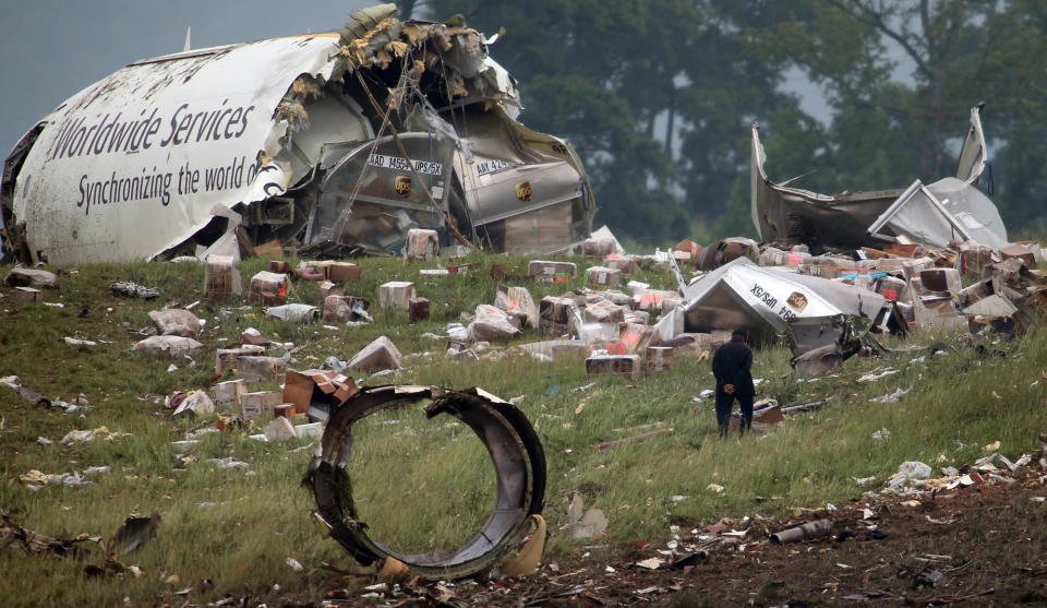 FILE - In this Aug. 14, 2013, file photo, a investigator looks through debris of a UPS A300 cargo plane after it crashed on approach at Birmingham-Shuttlesworth International Airport in Birmingham, Ala. Federal investigators are looking at pilot fatigue, among other issues, as a possible factor in the fatal predawn crash of a UPS cargo jet. The National Transportation Safety Board scheduled a hearing for Feb. 20, 2014, on the accident, which killed both pilots. (AP Photo/Hal Yeager, File)