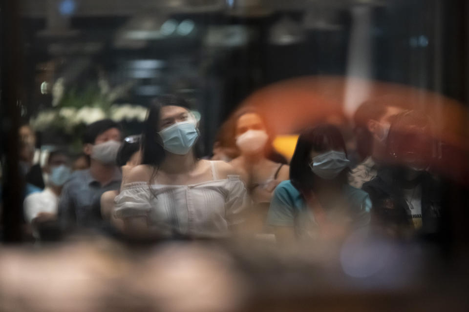 Lune Loh, 25, a transgender woman, is seen in a reflection on windows while attending an open mic night for poets in Singapore, on Thursday, Aug. 18, 2022. Poetry has been a lifeline for Loh. In between military exercises, she often lay in her bunk, typing poems into her phone. After her shifts, she put on makeup and a wig and went to open mic nights around the city that drew members of the LGBTQ community. (AP Photo/Wong Maye-E)