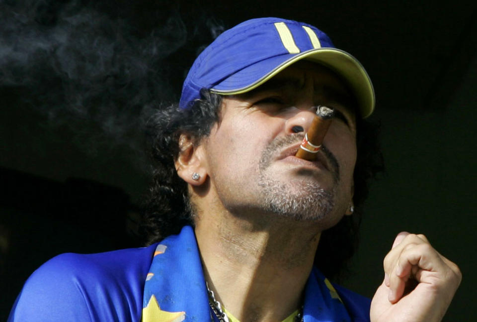 FILE - In this March 26, 2006 file photo, former soccer player Diego Maradona smokes a cigar as he watches Argentina's first division soccer match between Boca Juniors and River Plate in Buenos Aires, Argentina. The Argentine soccer great who was among the best players ever and who led his country to the 1986 World Cup title before later struggling with cocaine use and obesity, died from a heart attack on Wednesday, Nov. 25, 2020, at his home in Buenos Aires. He was 60. (AP Photo/Natacha Pisarenko, File)