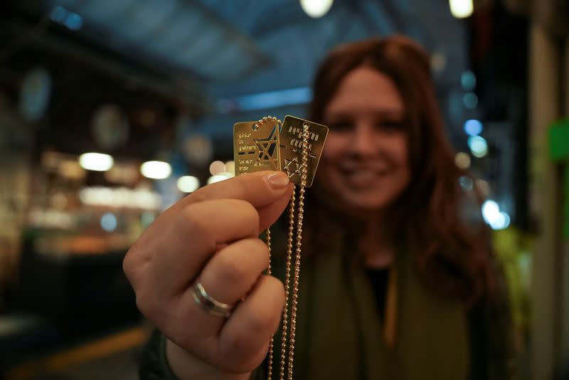 A woman holds up a military-style dog tag calling for the return of Israeli hostages who have been held in the Gaza Strip since they were seized by Hamas gunmen on October 7, at Mahane Yehuda market in Jerusalem