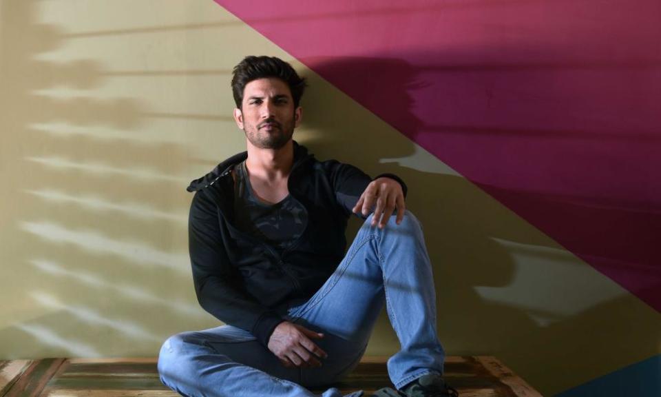 Portrait of Sushant Singh Rajput photographed sitting against a multicoloured wall