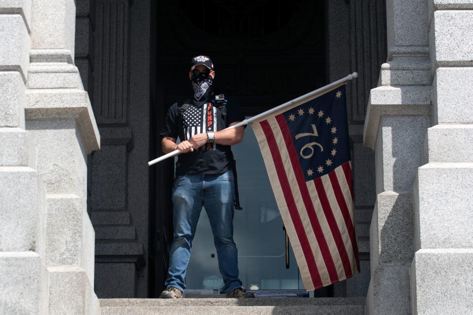 A demonstrator waves a Bennington flag as he gathers with others to protest coronavirus stay-at-home orders during a "ReOpen Colorado" rally in Denver, Colorado.